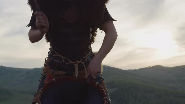 Drummer Taps Tambourine Against Distant Mountains at Sunset