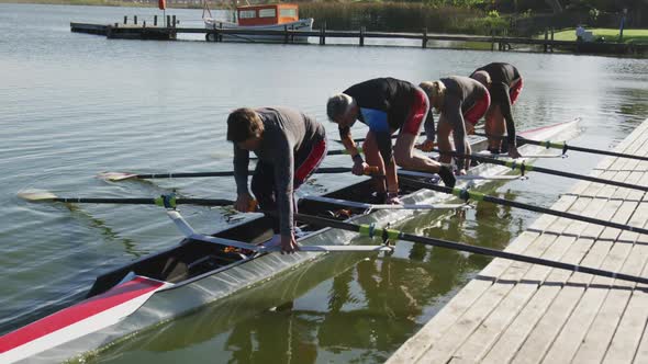 Four senior caucasian men and women preparing rowing boat in a river