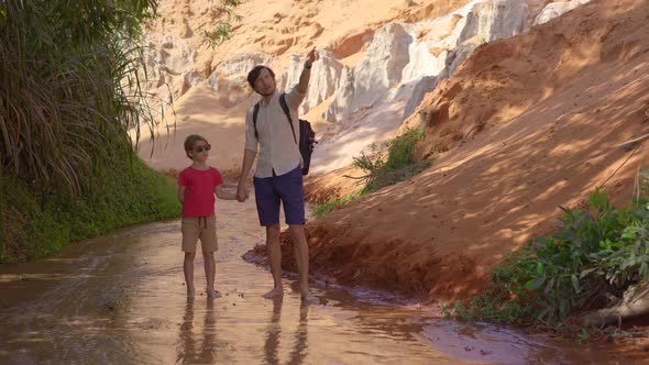 A Family Walks Along a Red Canyon or Fairy Stream at the Border of Desert in the Mui Ne Village in