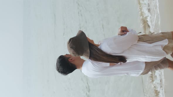 Vertical Video: Happy Asian couple walking at the seaside and enjoying on vacation summer.