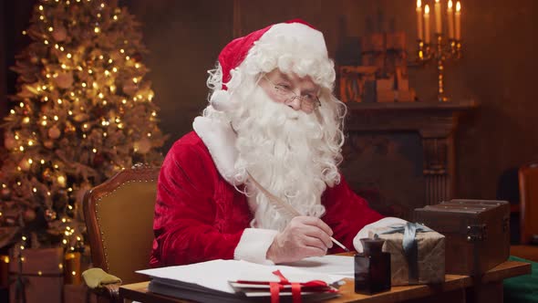 Workplace of Santa Claus. Cheerful Santa is working while sitting at the table.