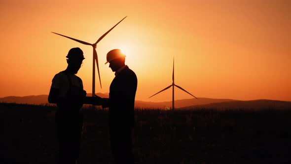 Silhouette Engineer and Inspector Working Together on Windmill Farm