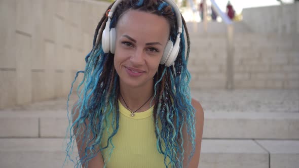 Portrait of a Cheerful Modern Young Woman with Headphones and Dreadlocks