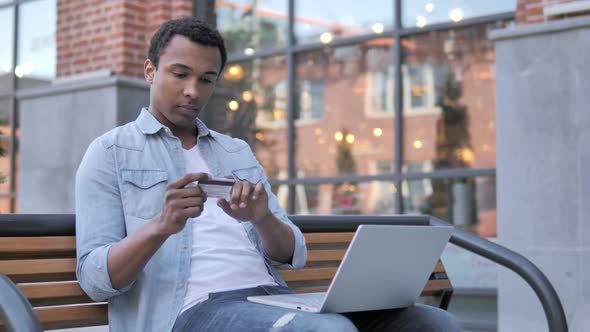 Online Shopping Failure for African Man Sitting on Bench