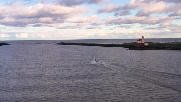 Drone follows a fishing boat leaven Bandon harbor on the Coquille River. Lighthouse at Bullards beac