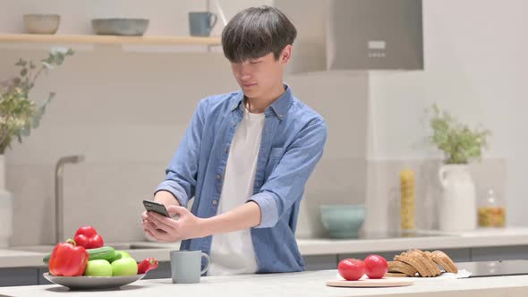 Asian Man Taking Picture of Fruits on Smartphone in Kitchen