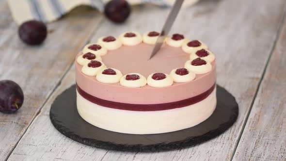 Cutting Delicious Plum Mousse Cake with Whipped Cream