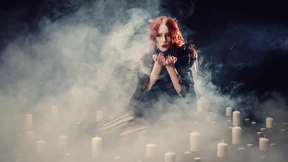 Young Red-haired Girl with Devil Horns and in Black Suit in Dark Room with Smoke Sitting on Floor
