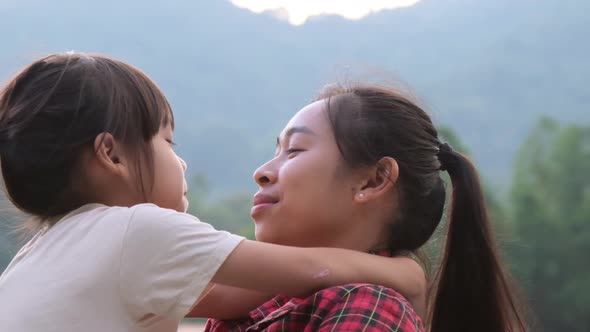 Happy little daughter hugs and kisses her mother in the park. family relationship concept