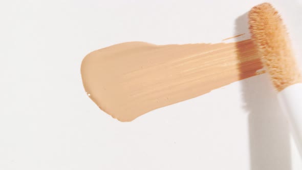 Macro Shot and Slow Motion of a Brush Applicator Smear Concealer Isolated on White Background