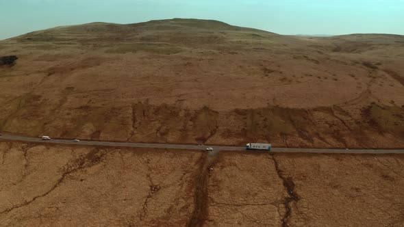 Abstract aerial view of country road with few cars in front of the brown dried up field