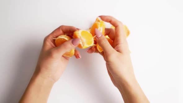 Peeled mandarin in female hands. Close up of mandarin on white background