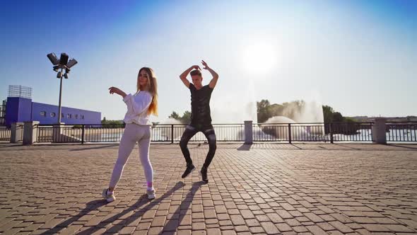 Young dancers moving in tact. Boy and girl dancing together outdoors.