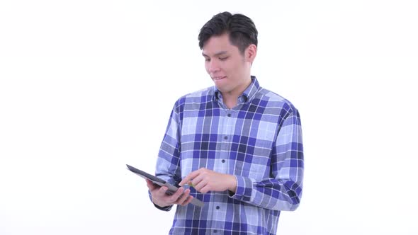 Happy Young Asian Hipster Man Thinking While Using Digital Tablet