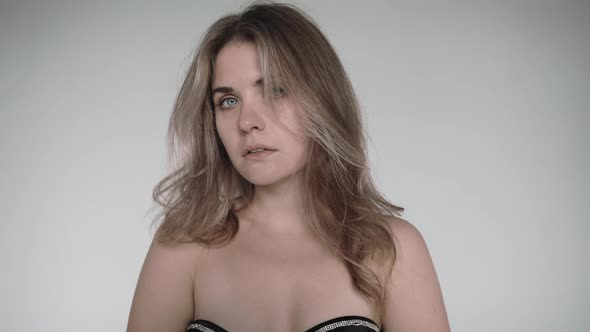 Blonde Woman Looks at the Camera Wearing Black Lingerie on a White Background