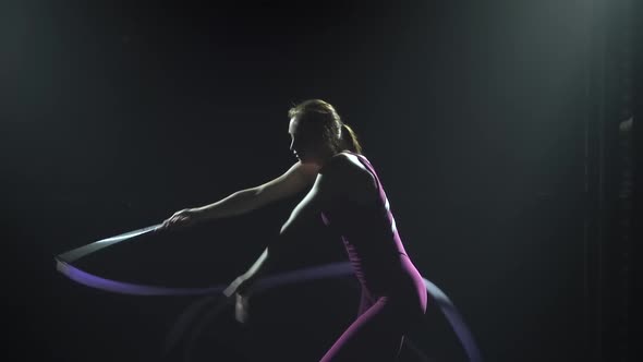 Silhouette of a Slim Young Female Gymnast in Tight Fitting Body Doing the Gymnastics Exercise with