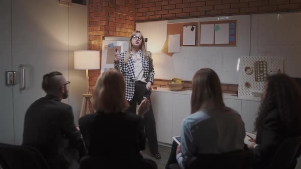 Female Manager Presents New Project Plan To Colleagues at Meeting, Explaining Ideas on Flipchart To