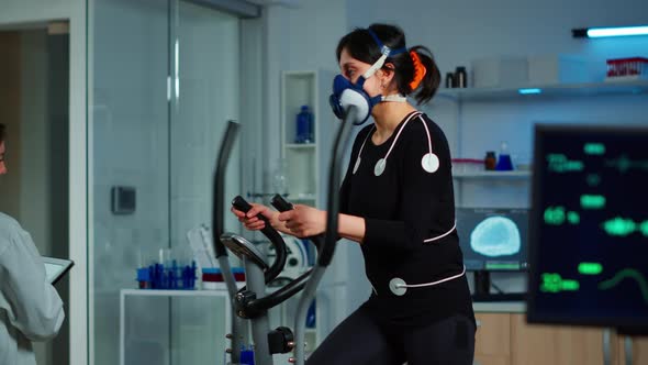 Woman Athlete with Mask Running on Cross Trainer in Sports Science Lab