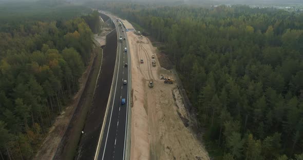 New Highway Road Construction Between Green Forest Aerial View at Sunrise