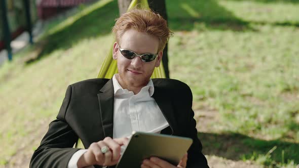 Carefree Man in Business Suit Using Tablet in Hammock