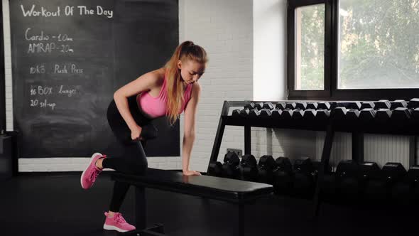 Athletic girl athlete trains her back with dumbbells in the gym. Dumbbell bench press