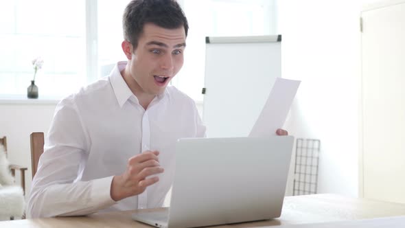 Excited Businessman Celebrating Results During Paperwork at Work