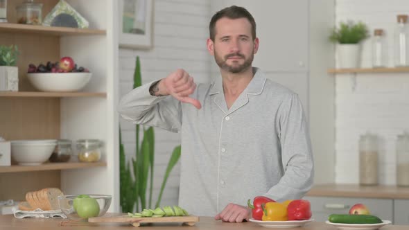 Young Man Showing Thumbs Down While Standing in Kitchen