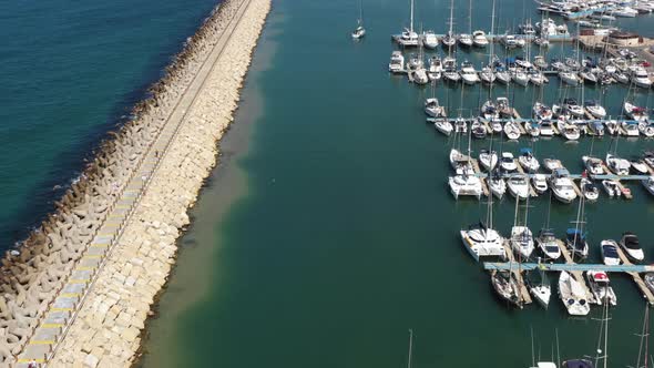 Several sailing yachts sail calmly through the marina of Herzeliya while several small waves are lap