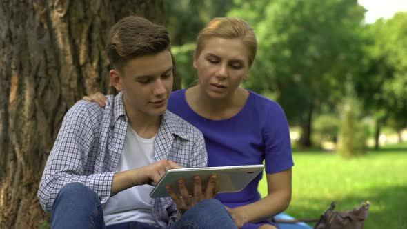 Son Showing Mom How to Use Banking and Pay Bills via Tablet