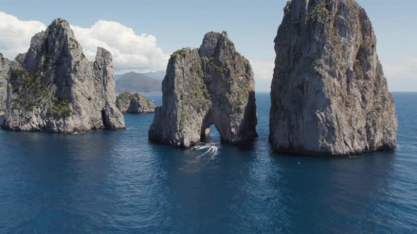 Aerial of Yachts Boating Under the Natural Arch of the Faraglioni Sea Stacks on Coast of Capri Islan