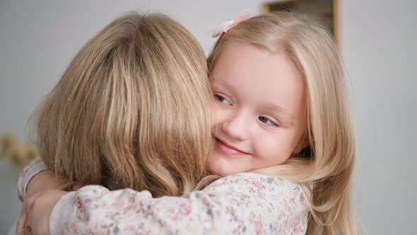 Happy Family Adorable Smiling Little Girl with Love and Tenderness Hugs Her Loving Mother While