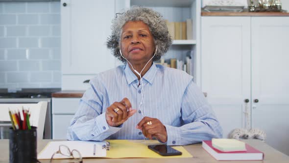 Portrait of senior african american female doctor talking while having a video call at home