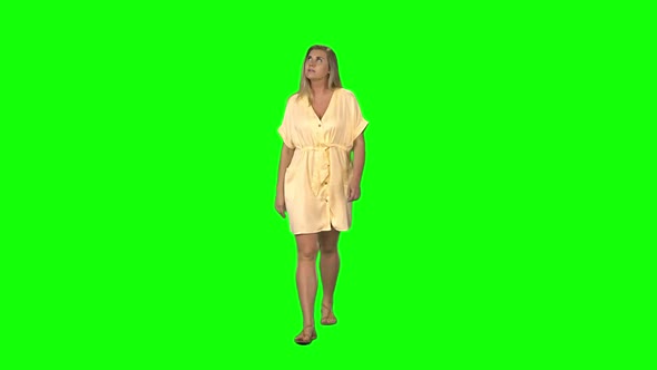 Tanned Blond Woman Is Calmly Walking and Smiling on Green Screen. Chroma Key. Front View. Slow