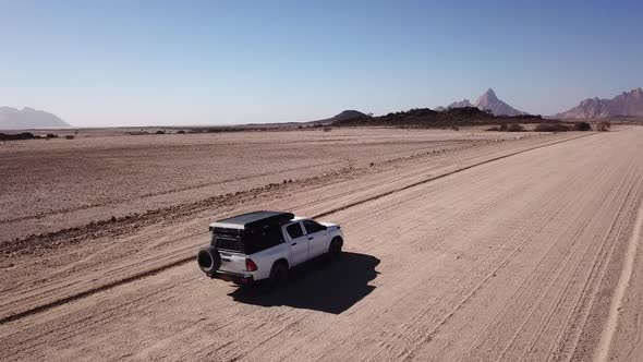 Car Driving on Gravel Road in Aerial Desert