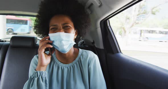 African american businesswoman with face mask talking on smartphone