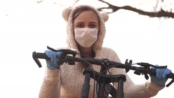 Portrait of Young Woman in Medical Mask and Gloves with Bicycle Against Sky