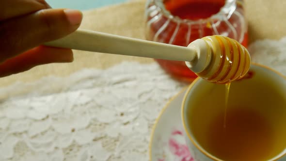 Hand pouring honey in herbal tea 4k