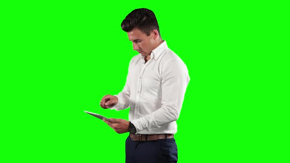 a Caucasian man in suit using a tablet in a green background