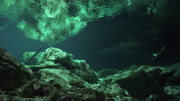 Scuba diver reaching the exit of Cenote cave system Tajma Ha in Yucatan Mexico with rock formations