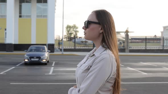 Beautiful Young Girl with Glasses Walks Through the City and Looks Around