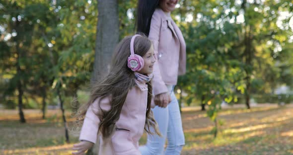 Young Mother with Her Little Daughter Running in the Park