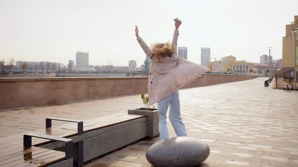Great News  a Woman with a Smartphone in Her Hand is Jumping with Happiness