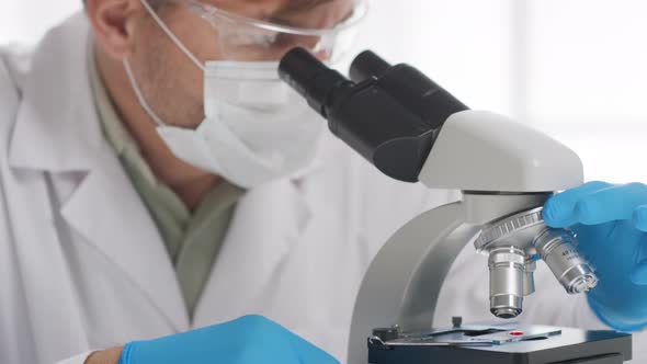 Male Biomedical Scientist Looking into Microscope