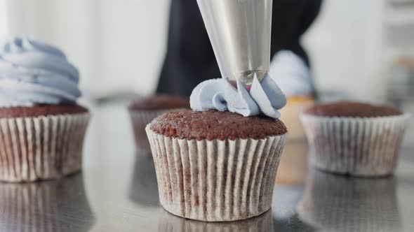 Closeup of Blue Muffin Topping Pouring From Confectionery Syringe on Top of Sweet Tasty Dessert