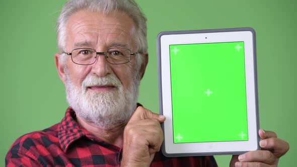 Handsome Senior Bearded Man Against Green Background