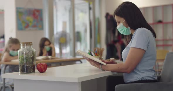 Children in the Classroom at School in Masks Sit in the Classroom and Listening the Teacher