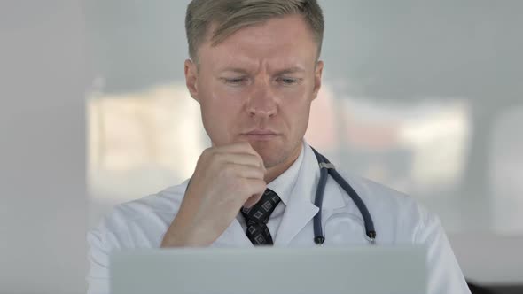 Pensive Doctor Thinking and Working on Laptop