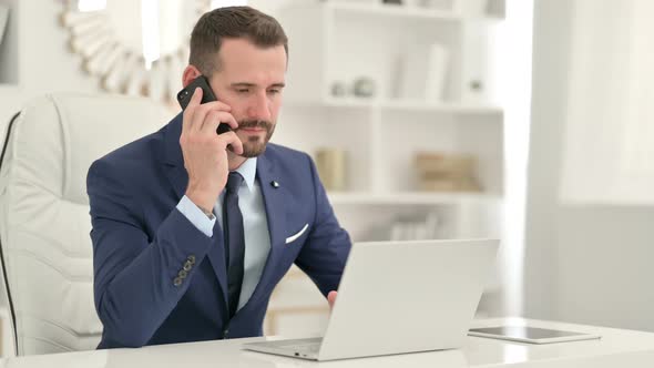 Cheerful Businessman Talking on Smartphone in Office 