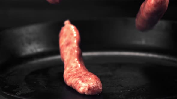 Super Slow Motion Raw Sausages Fall on the Pan