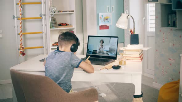 Little Kid Studying Online in Front of His Laptop at Home. Remote Education Caused By the Covid-19